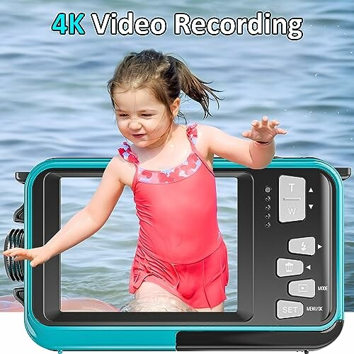 Child in red swimsuit on video camera display at the beach.